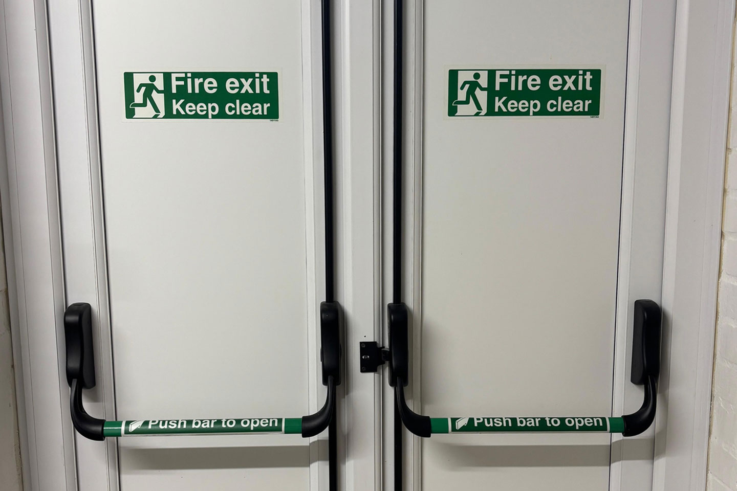 White Fire Exit Doors with push bars and green keep clear signs