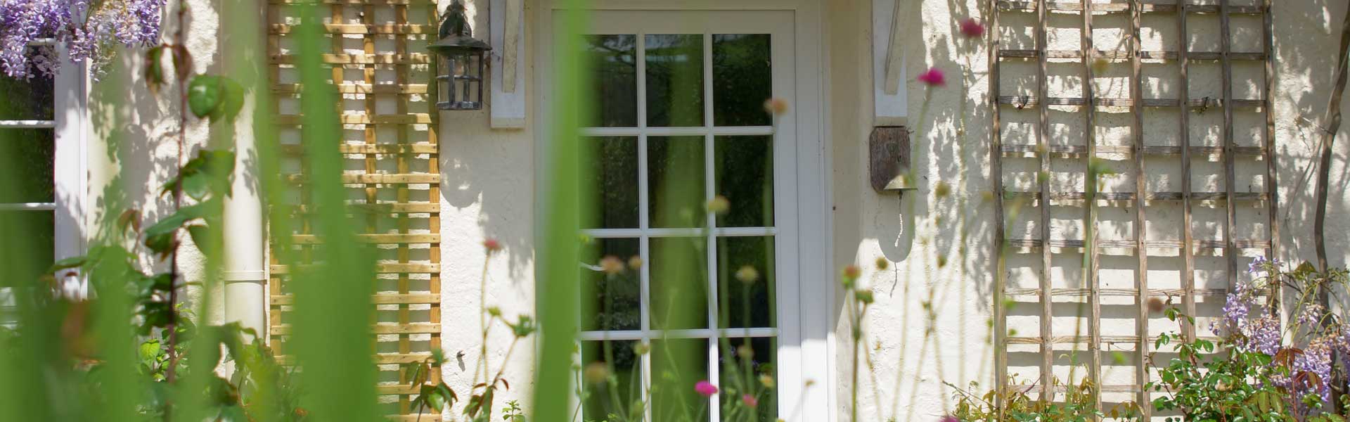 White coloured uPVC Door surrounded by plants and Wisteria