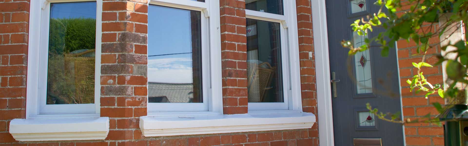 Dark grey fitted door and white coloured bay windows bt Woodstock Windows