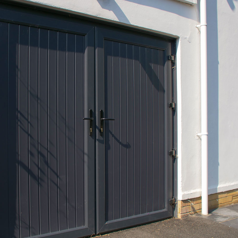 Dark grey garage doors and white upvc guttering and downpipe